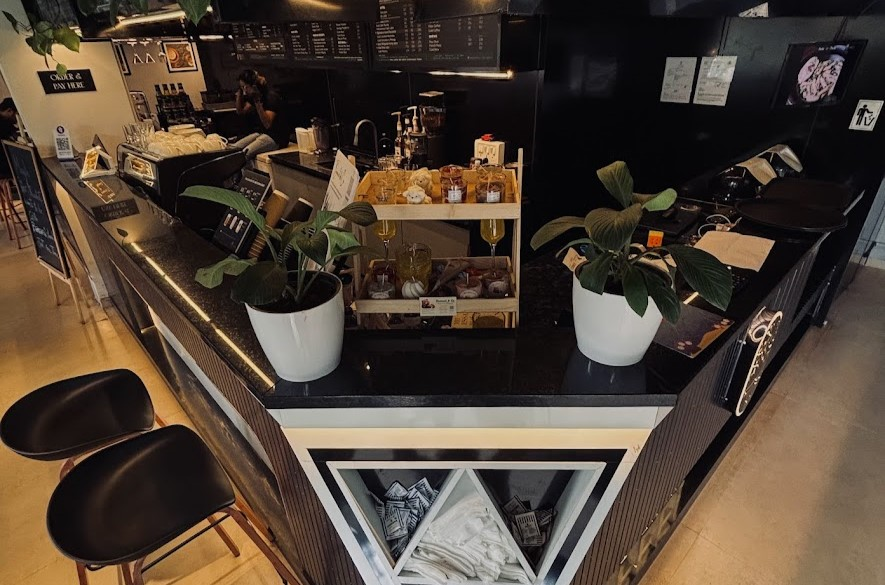 The Abrista coffee counter with plants, pastries, and warm lighting