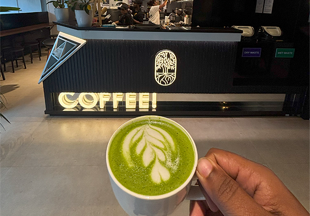 A matcha latte held in front of the Abrista coffee bar